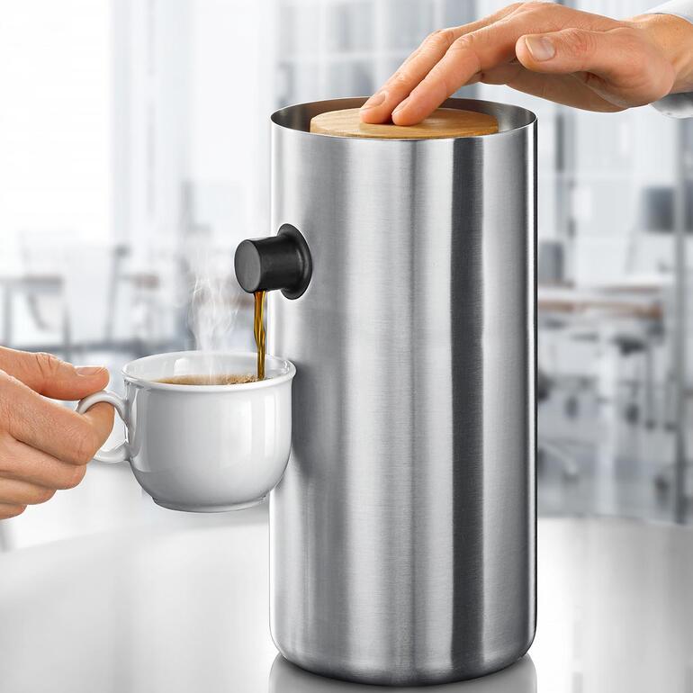 La combinaison de l’acier inox froid et brillant et du bois de chêne chaud et naturel confère une esthétique particulière à cette verseuse à pompe. Cafetière design en acier inoxydable avec de la vapeur et une tasse.