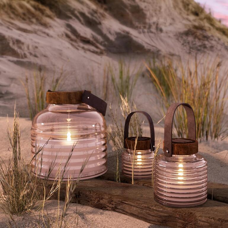 Trois lanternes solaires dans un cadre de plage sablonneuse