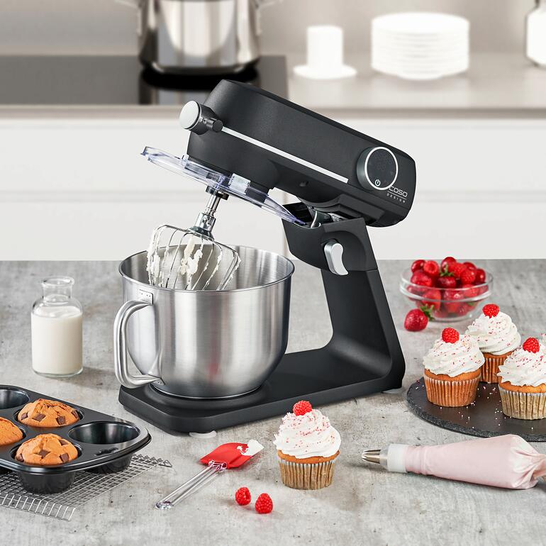 Robot de cuisine Caso KM 1.800 avec un bol à pâte et des pâtisseries sur un comptoir de cuisine.