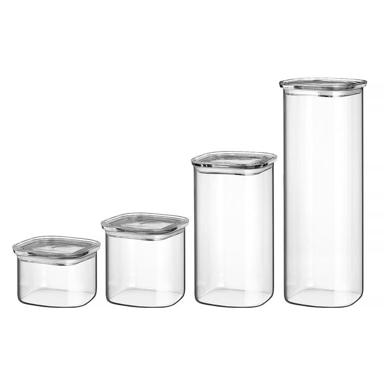 Quatre bocaux de stockage transparents avec couvercle en verre de différentes tailles sur un fond blanc.