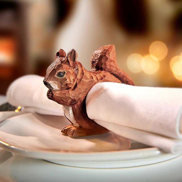 Anneau de serviette en bois en forme d'écureuil sur une table avec une serviette.