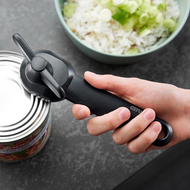 Ouvre-boîte en main au-dessus d'une boîte de conserve ouverte