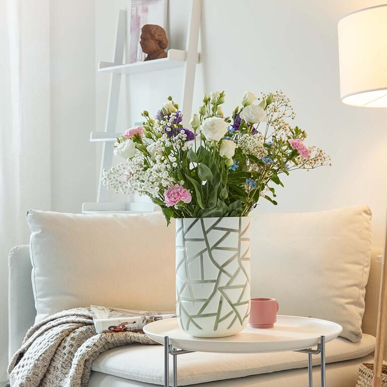 Vase avec des fleurs colorées et des objets en céramique sur une table