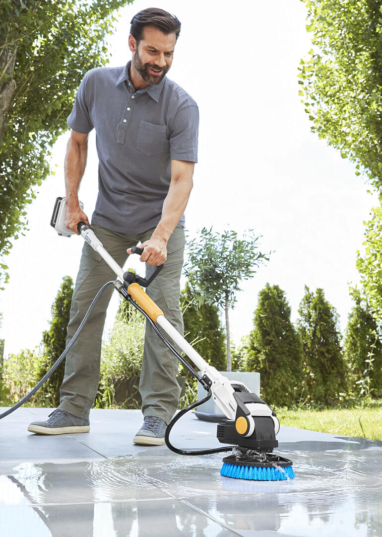 Homme utilisant le Twin Brush électro-nettoyeur sur une terrasse en extérieur.