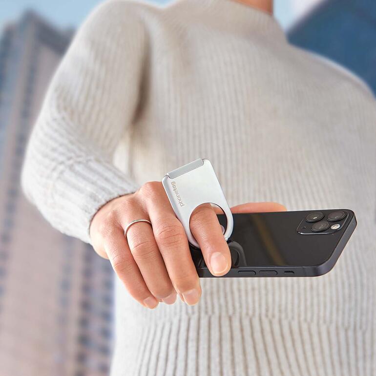 Vous tenez votre smartphone toujours bien en main, de manière sécurisée et décontractée, pour téléphoner, lire ou écrire un message. Personne tenant un smartphone avec un support en anneau.