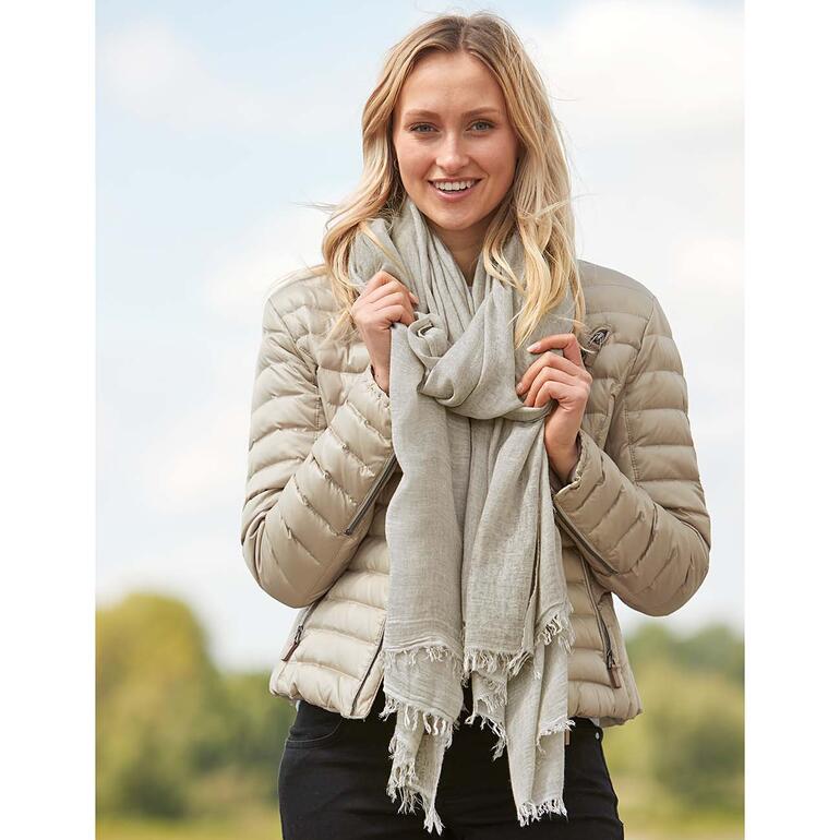 Portée comme une écharpe, la couverture vous enveloppe de manière très subtile et douillette. Femme portant une couverture polyvalente comme écharpe en pleine nature, souriante.