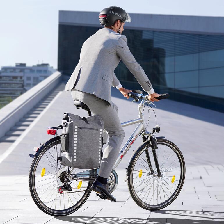 Homme en costume faisant du vélo avec un sac à dos 4-en-1 imperméable.