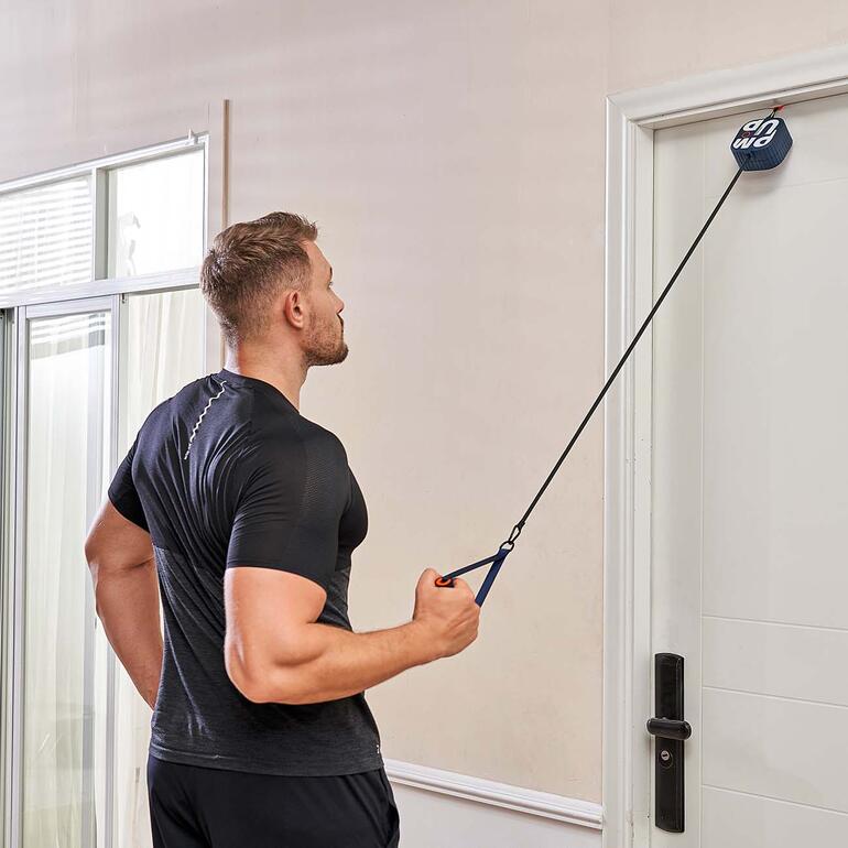 Homme avec les cheveux courts tirant sur l'appareil Pocket-Gym dans une porte.
