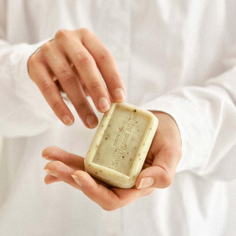 Disponible dans une version Merlot et une version Sauvignon Blanc. Une personne tenant le savon The Real Wine Soap® dans sa main.