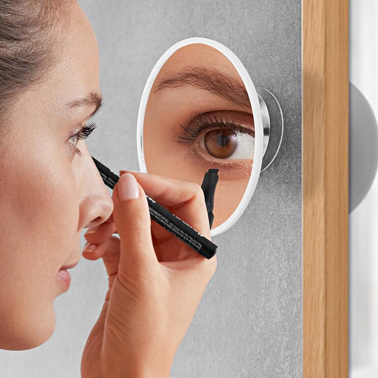 Gros plan d'une femme qui se maquille avec un miroir de maquillage.