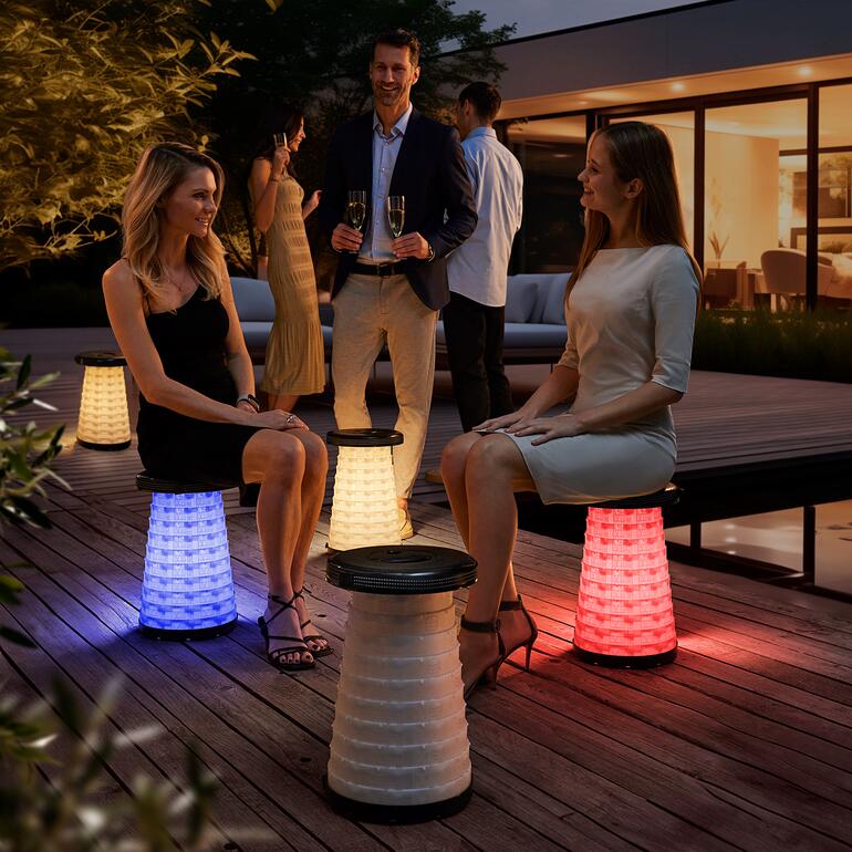Deux femmes sont assises sur des tabourets télescopiques LED lors d'une soirée jardin.