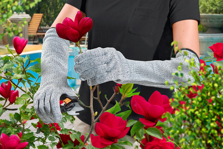 Jardinier avec des gants de jardinage Safety coupant une fleur.
