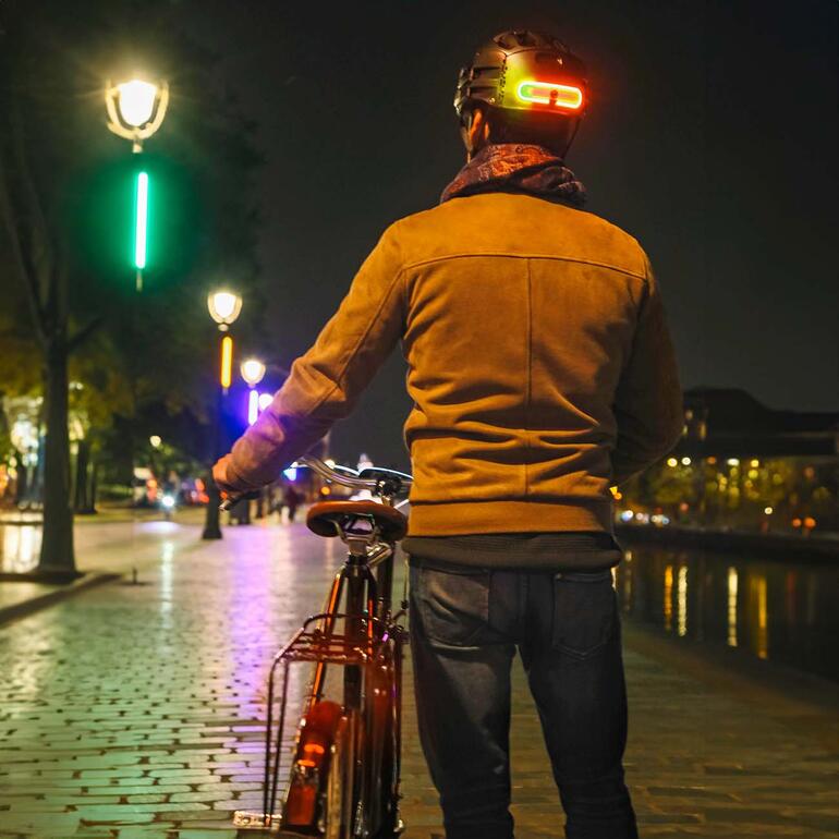 Personne avec un vélo et une lumière de frein avec clignotant dans la ville la nuit.