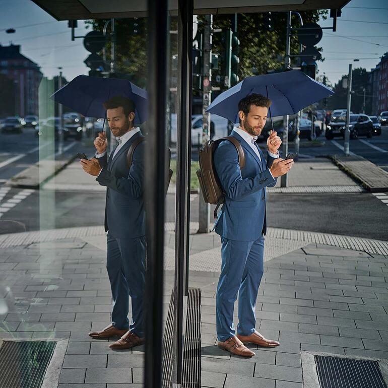 Homme en costume avec un parapluie ultraléger dans la rue