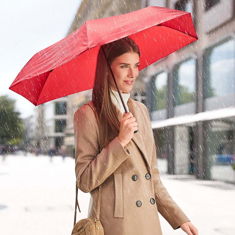 Rouge Femme tenant un parapluie léger rouge sous la pluie