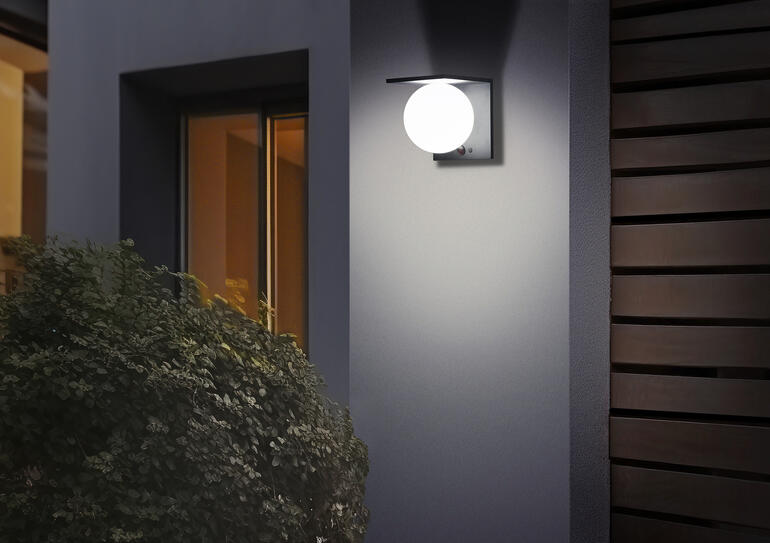 Applique murale solaire avec boule illuminant doucement un mur.