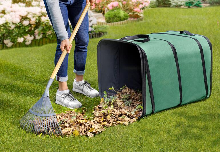Personne balayant des feuilles dans un collecteur de déchets de jardin carré sur l'herbe