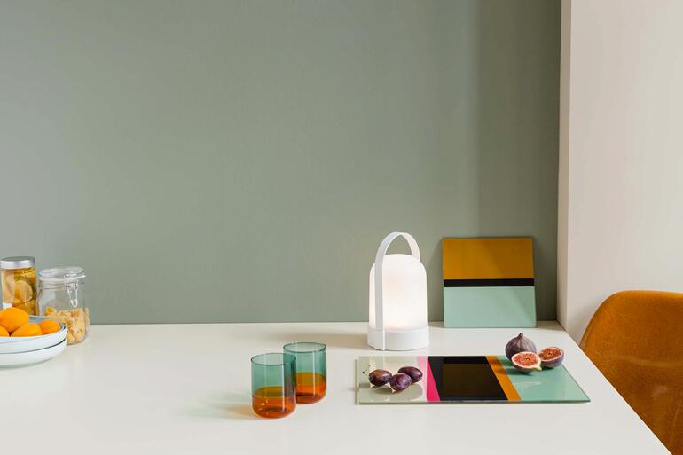 Lampes à batterie Piccolos et Grande sur une table avec des verres colorés.