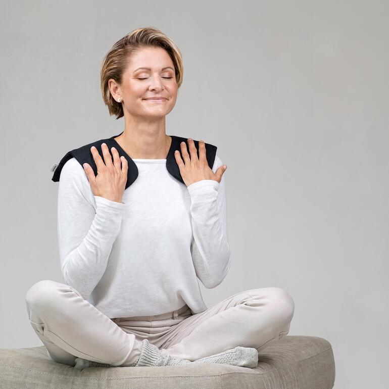 Femme avec un coussin de tourbe sur les épaules, détendue