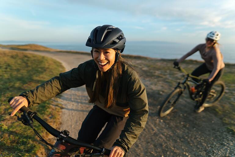Femme riant sur son vélo, portant un casque avec un système d'intercom.