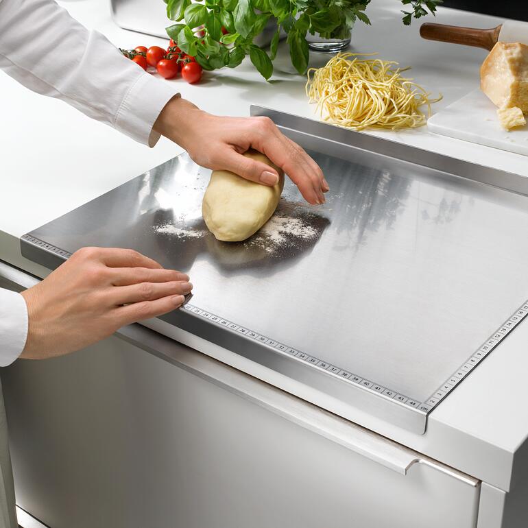 Personne étale de la pâte sur un plan de travail en acier inoxydable