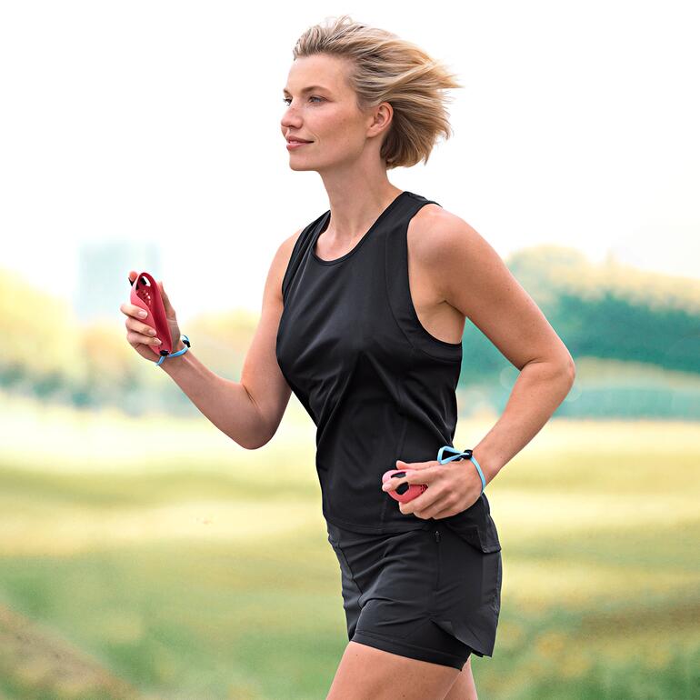 Femme courant à l'extérieur, portant des vêtements de sport et tenant une Laufmaus dans la main.