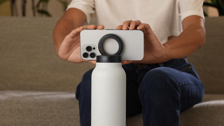 Personne tenant une bouteille 2-en-1 avec un smartphone en équilibre dessus.