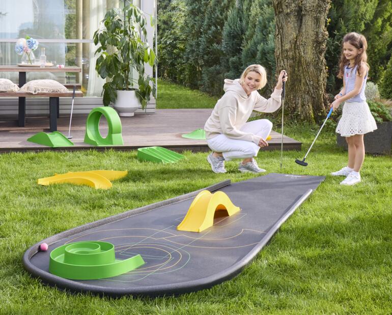 Femme et enfant jouant au mini-golf sur un parcours portable.