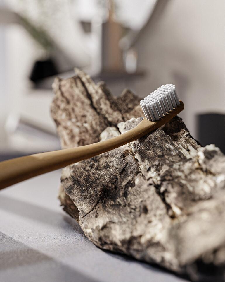 La tête de brosse est composée de 6 750 filaments thermoplastiques fins et le manche est fabriqué à partir de lignine, un composant naturel du bois. Brosse à dents en bois sur un fond sobre.