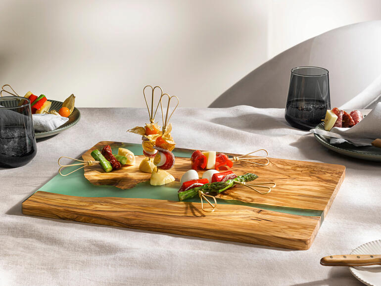 Le design rivière varie toujours et fait de chaque planche une pièce unique incomparable. Planche de service River-Design avec des brochettes de légumes dessus