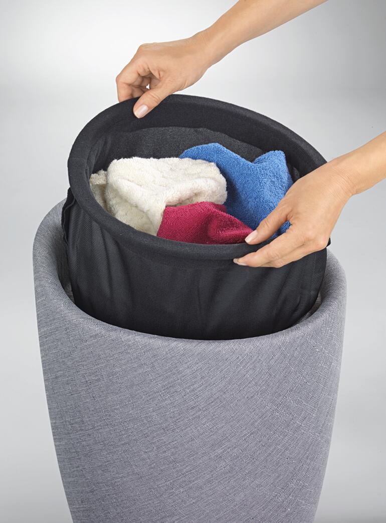 Sac de linge avec poignées latérales – pour un retrait aisé. Mains en train de retirer des serviettes colorées d'un panier à linge.