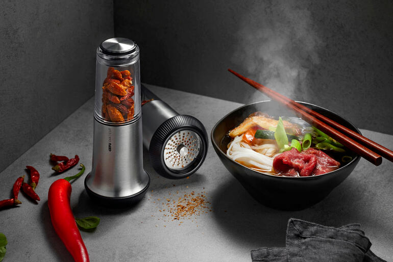 Coupe-chili X-Plosion® à côté d'un bol avec de la nourriture fumante