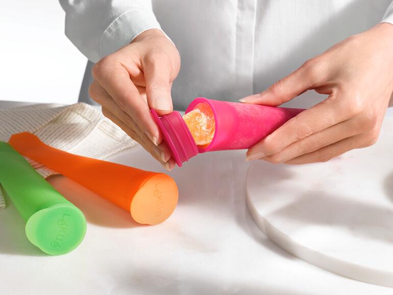 Les glaces sont très facilement extraits des tubes en silicone flexible. Mains retirant de la glace congelée d'un moule à glace en silicone coloré