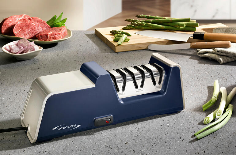 Affûteur de couteaux électrique en diamant sur un comptoir de cuisine avec des ingrédients.