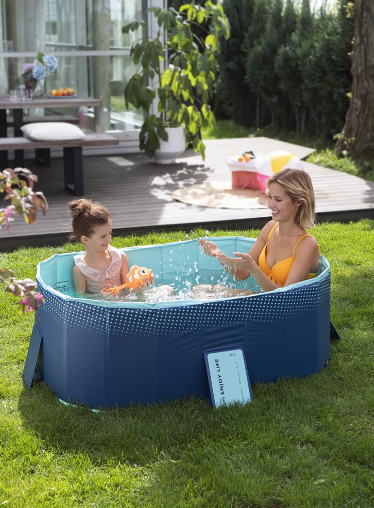 Piscine pliable avec mère et enfant dans l'eau, entourée d'une pelouse verte.