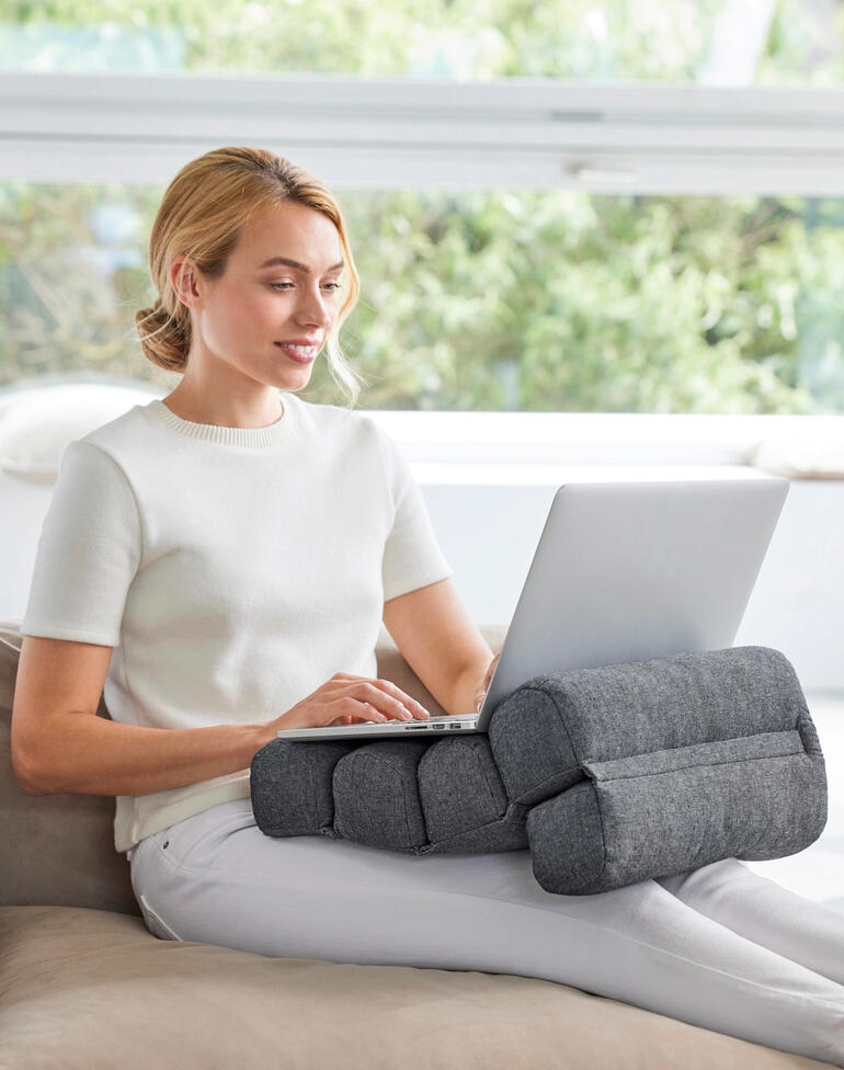 Idéal en tant que coussin de dos confortable et soutien des cervicales en travaillant, conduisant … Femme assise avec un coussin flexible soutenant ses bras, sur le canapé avec un ordinateur portable.