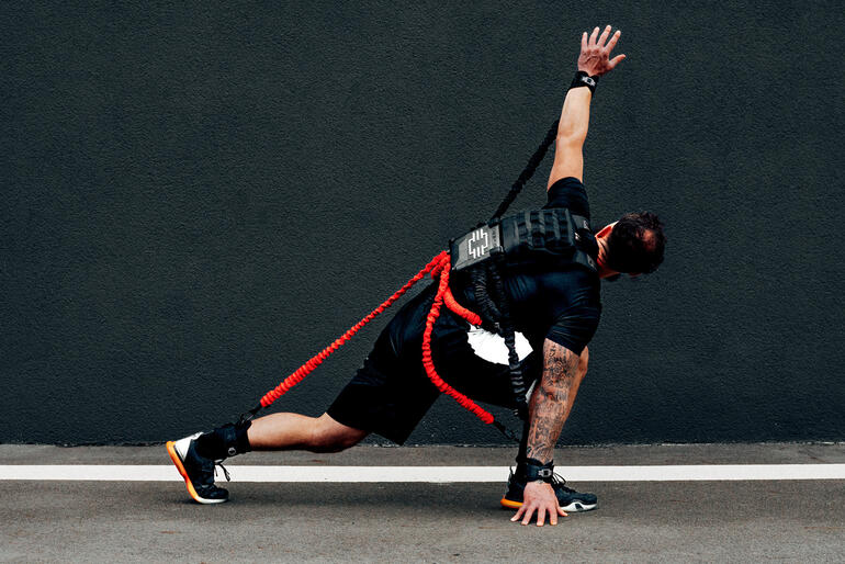 Homme en posture sportive avec un set d'entraînement de résistance sur un fond urbain.