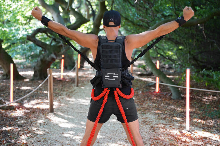 Homme avec un ensemble d'entraînement de résistance levant les bras à l'extérieur.