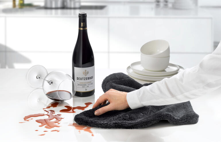 Chiffon de séchage et de nettoyage professionnel sur le plan de travail de la cuisine avec du vin et des verres.