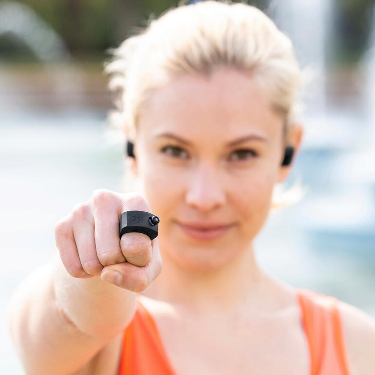 Il suffit de passer la bague ArcX sur votre index – et votre téléphone portable reste bien rangé. Femme montrant la télécommande ArcX Mini sur son doigt.