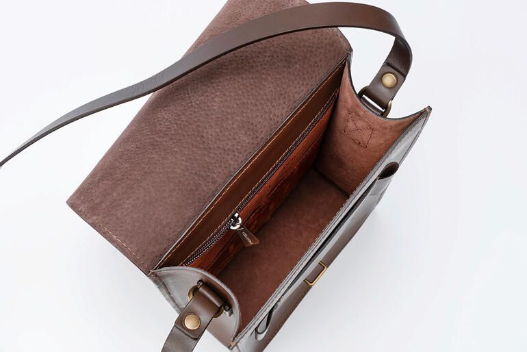La sacoche à cartes dispose d’un compartiment principal spacieux avec une pochette zippée et deux compartiments. Vue intérieure d'un sac à carte Chiarugi marron avec une poche zippée.