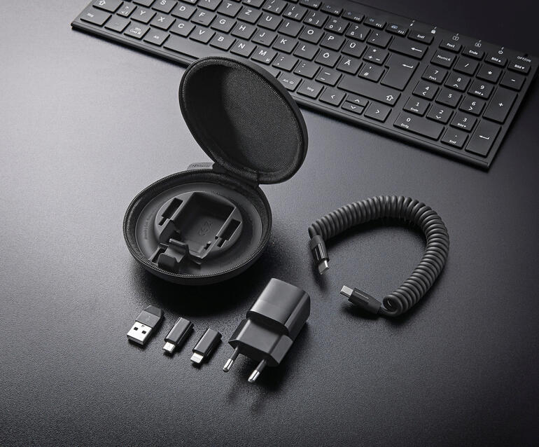 L’étui rigide contient : un adaptateur secteur GaN 30 W, un câble spirale USB-C (avec une puissance de charge jusqu’à 60 W) et un adaptateur USB-A, un micro-USB et un Lightning. Kit de chargement tout-en-un sur un bureau, avec câble et adaptateurs.