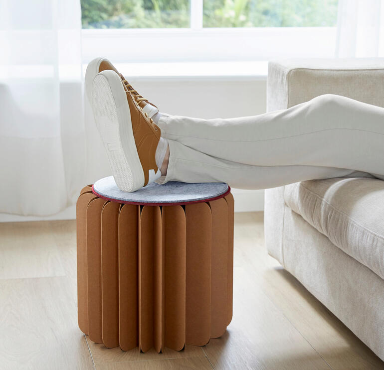 Femme avec un pouf Bookniture utilisé comme repose-pieds.