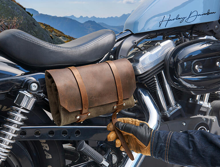 Trousse à outils en cuir véritable fixée à une moto, avec une main gantée à côté