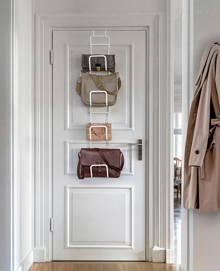 Support de sacs variable accroché à une porte avec des sacs.