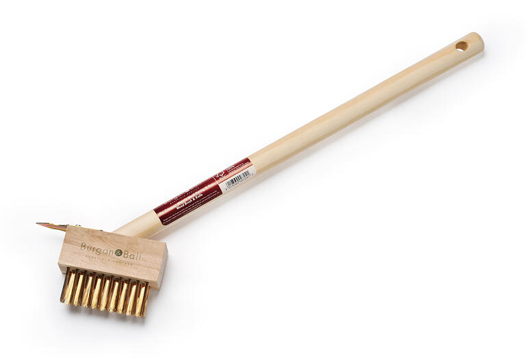 Brosse de joint contre les mauvaises herbes avec un long manche en bois et des poils courbés.