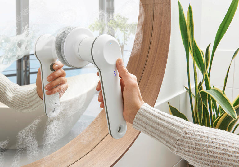 Brosse de nettoyage à main rechargeable utilisée pour nettoyer un miroir.