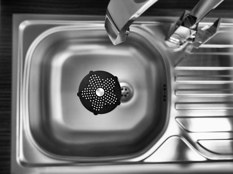 Le tamis d’évier, de la taille d’une paume de main, est parfait pour un évier, une douche, une baignoire, au-dessus d’une évacuation au sol ... Vue du dessus sur un filtre d'égouttement noir dans un évier.