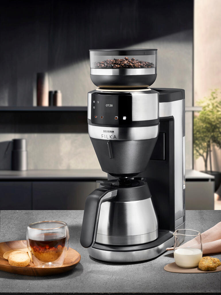 Machine à café filtre FILKA avec une tasse de café et du lait sur une table.