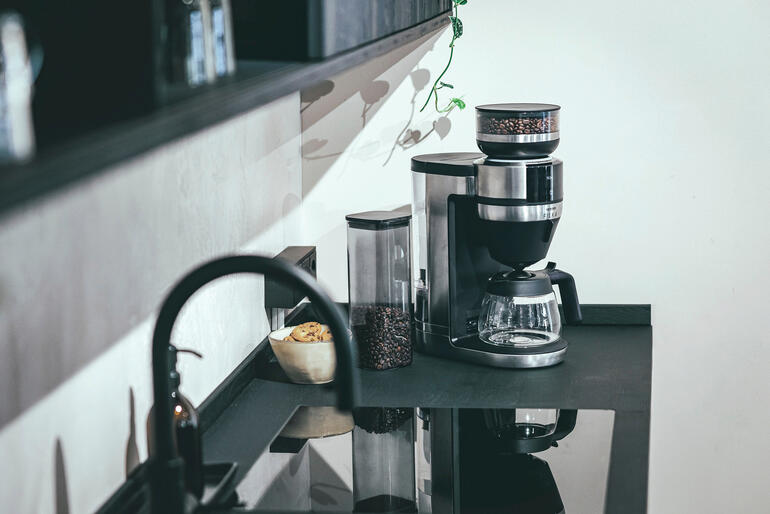 Également disponible avec une verseuse en verre. Machine à café filtre FILKA sur un plan de travail de cuisine moderne.
